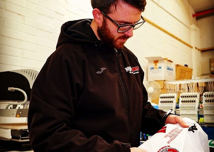 Jason-from-MJM-Sports-checking-quality-of-a-custom-printed-football-shirt-702x500
